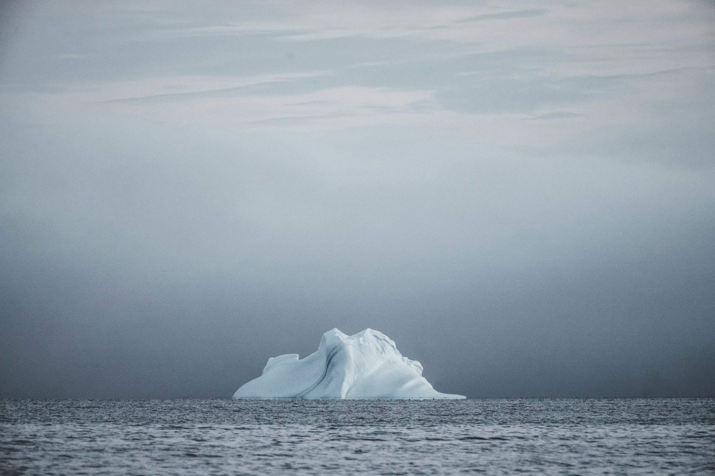 A single iceberg floating in still Arctic water off Greenland